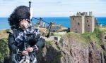 man playing bag pipe with castle in background